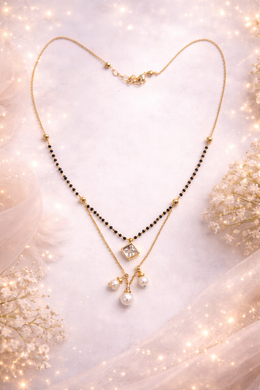 Gold necklace with black beads and pearls on a soft, blurred background
